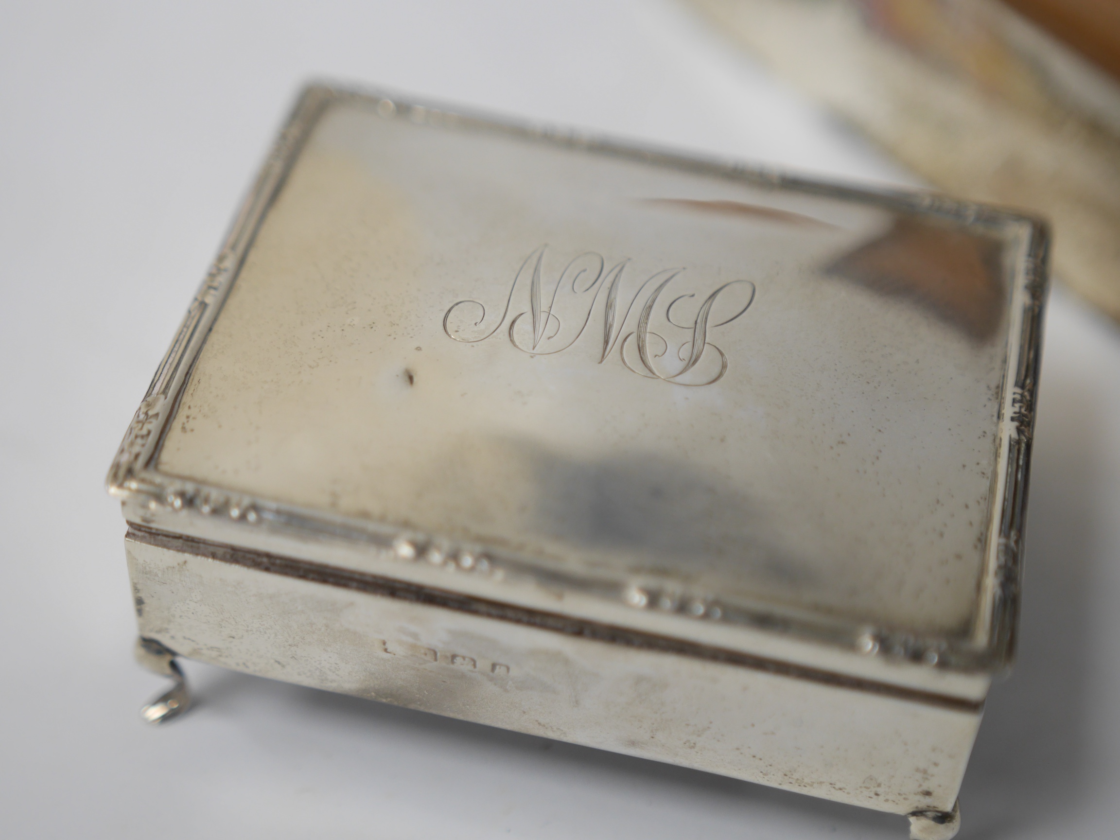 A George V silver mounted rectangular cigarette box, London, 1926, 25.9cm, together with an Edwardian silver mounted cigarette box (ex trinket box?). Condition - fair